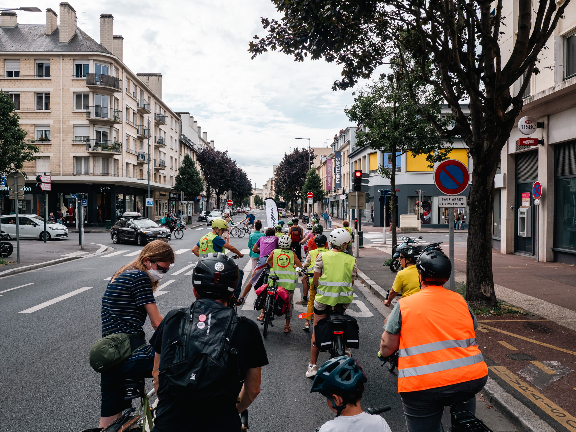 Cortège de cyclistes vue de dos. Attendant que le feu passe au vert au croissement entre la Rue de Bernières et la Rue Saint-Jean à Caen 